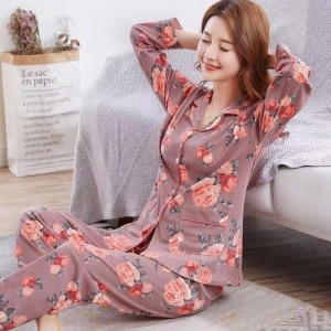 Pijama femenino de dos piezas de algodón con estampado floral, llevado por una mujer sentada en una alfombra en una casa
