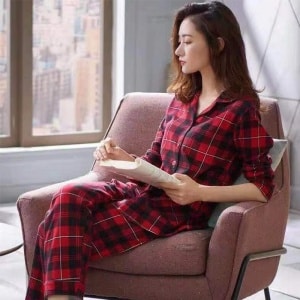 Pijama de primavera de dos piezas con estampado de cuadros para mujer que lleva una mujer sentada en una silla en una casa