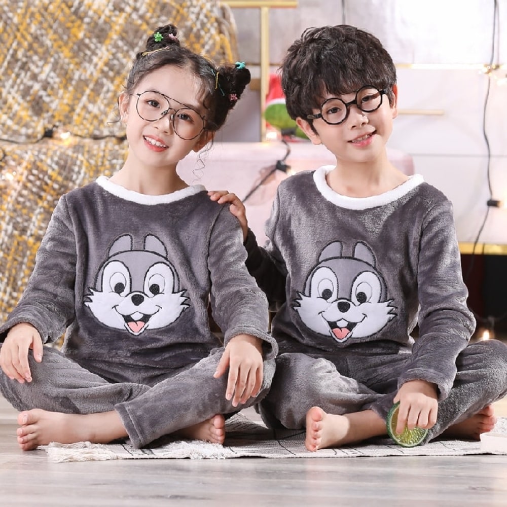 Pijama de franela de conejo Panpan para niños que llevan un niño y una niña sentados en una alfombra delante de una mesilla de noche en una casa