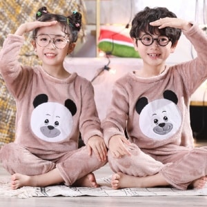 Pijama de franela de manga larga con estampado de panda para niños que llevan un niño y una niña sentados en la alfombra de una casa