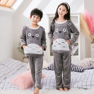 Pijama de forro polar gris con estampado de Toroto para niño que llevan un niño pequeño y una niña pequeña con diadema en la cama de una casa