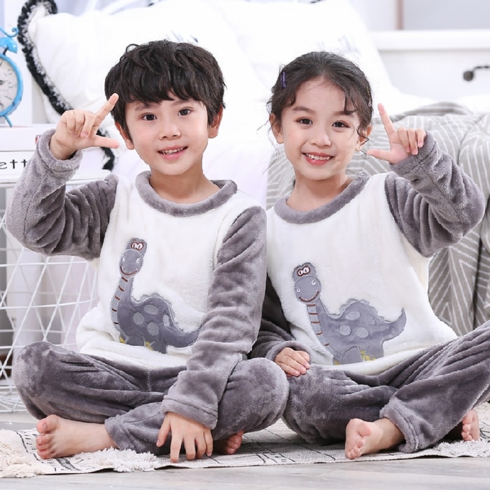 Pijama de dos piezas de franela gris con diseño de dinosaurios para niños que llevan un niño y una niña en una casa