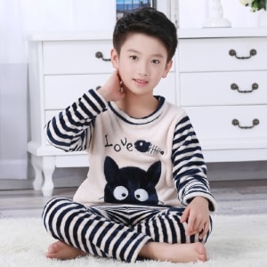 Pijama de franela de dos piezas a rayas blancas y negras para niño sentado en una alfombra en una casa