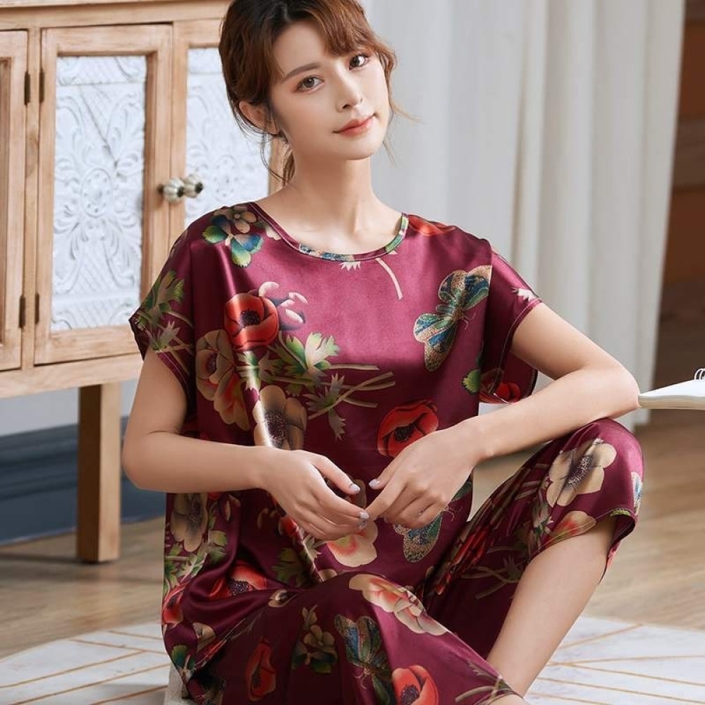 Pijama de verano de satén de seda rojo con estampado de flores para mujer que lleva una mujer sentada en una alfombra en una casa