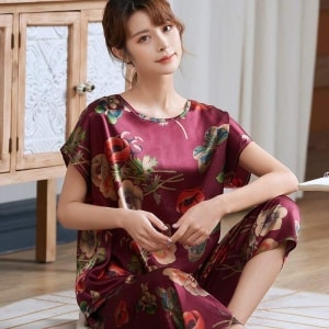 Pijama de verano de satén de seda rojo con estampado de flores para mujer que lleva una mujer sentada en una alfombra en una casa