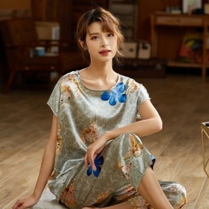 Pijama de verano de dos piezas de satén de seda gris con estampado floral de moda que lleva una mujer sentada en la alfombra de una casa