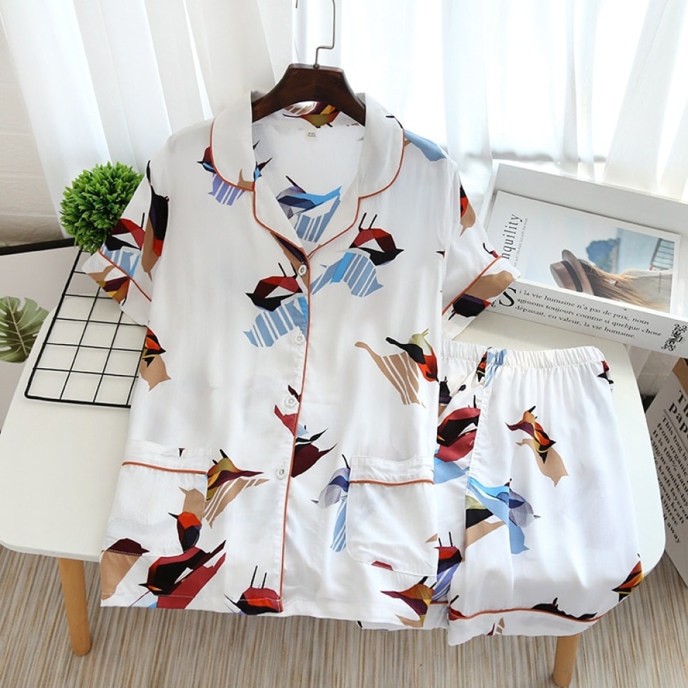 Pijama de verano blanco de manga corta con estampado de pájaros para mujer sobre una mesa con una revista como decoración