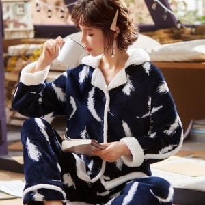 Pijama de forro polar grueso compuesto por un pantalón y una blusa gruesa. El color del pijama es azul. El pijama tiene un estampado de plumas blancas.