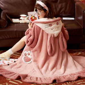 Pijama largo de forro polar con capucha para mujer con pelaje de conejito rosa y fondo de sofá