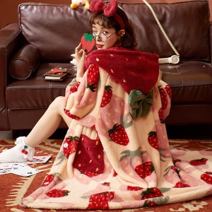 Pijama largo de vellón de fresa para mujer con una mujer que lleva el pijama de colores con un fondo de sofá
