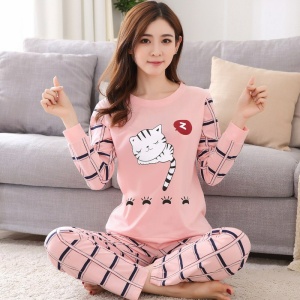 Bonito pijama de 2 piezas de manga larga para mujer que lleva una mujer sentada en una alfombra delante de una silla en una casa
