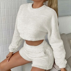 Conjunto de pijama corto con jersey blanco que lleva una mujer sentada en la cama de una casa