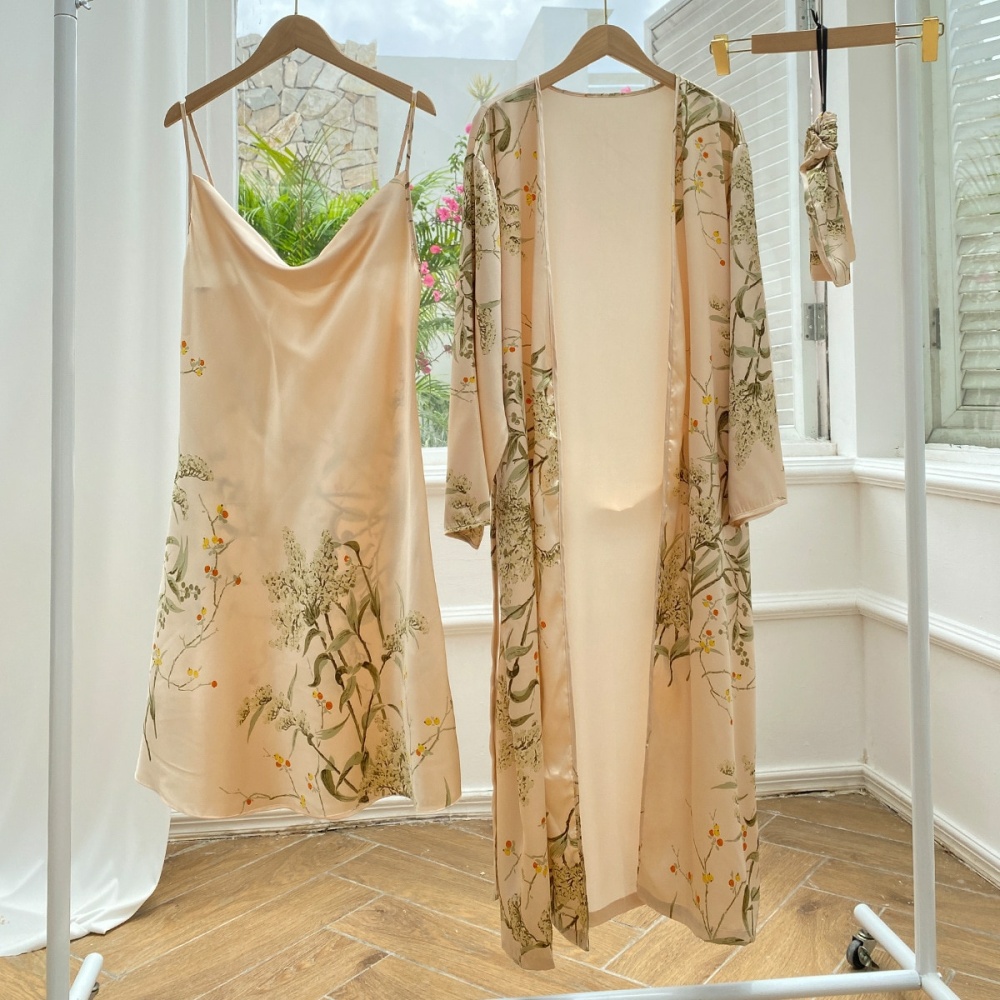 Pijama sexy beige con estampado floral colgado en perchas en una habitación con suelo de madera y pared blanca y frente a una ventana abierta