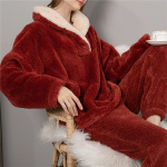 Pijama de vellón rojo que lleva una mujer sentada en una silla de madera con una taza de té en la mano