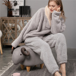 Pijama de forro polar gris que lleva una mujer sentada en un asiento con forma de oveja en un salón con paredes y suelos grises