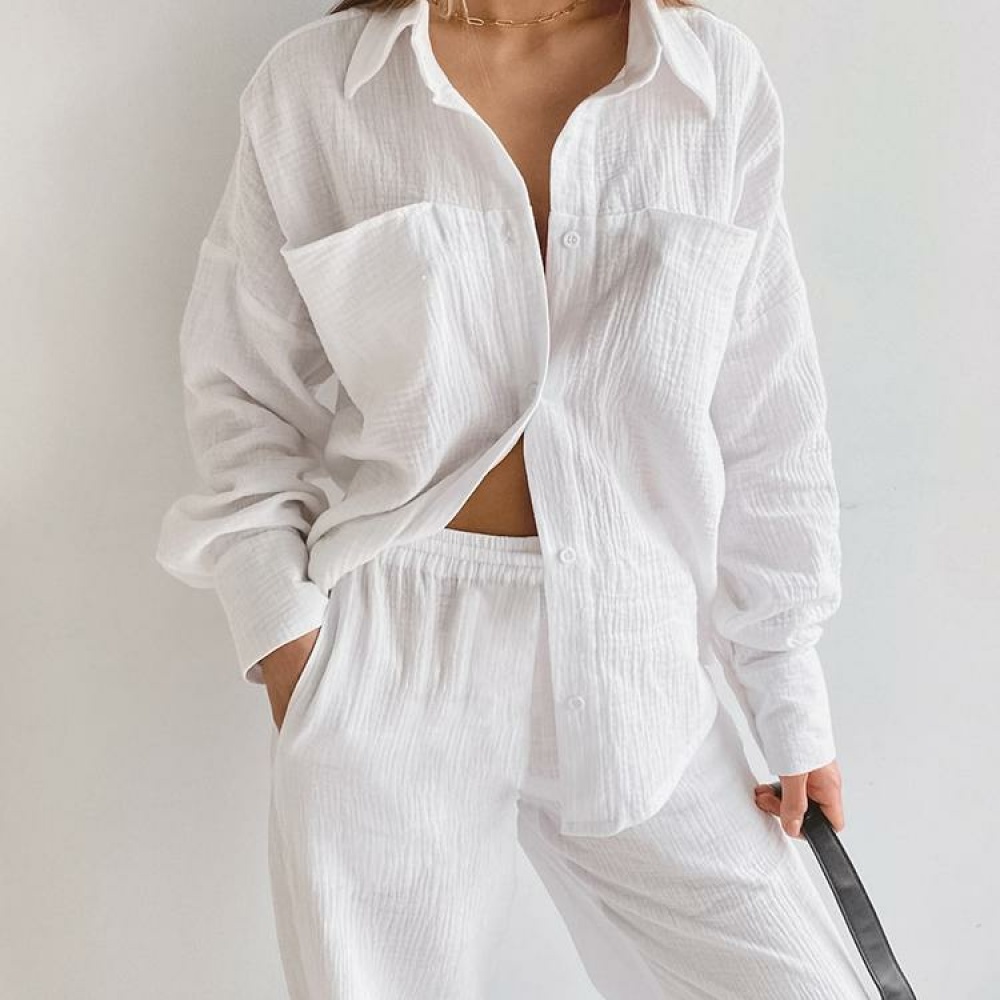 Pijama blanco de algodón llevado por una mujer contra una pared blanca