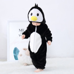 Bebé con pijama negro en forma de pingüino mirándose los pies